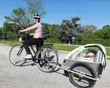 Donna in bici con rimorchio per bambini, pronta per le vacanze in bici con bambini.