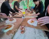 Bambini e adulti impastano farina e uova in una fattoria in Abruzzo, un'esperienza culinaria all'aperto.
