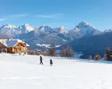 Un agriturismo con un gallo rosso sul tetto, immerso in un paesaggio innevato con montagne maestose.