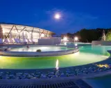 Piscine illuminate di notte a Chianciano Terme, con una luna piena nel cielo e persone che si rilassano nell'acqua calda.
