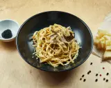 Un piatto di pasta al tartufo, un sapore autentico del cibo perugino, con scaglie di parmigiano e pepe nero.