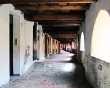 Portico con soffitto in legno e archi luminosi, pavimentazione in mattoni antichi. Un viaggio nella storia lungo la via degli asini a Brisighella.