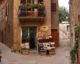 Un piccolo negozio di frutta e verdura in un vicolo di **paesi toscani**. Frutta fresca in cassette di legno, un balcone fiorito e l'atmosfera autentica.