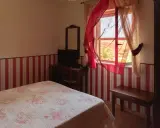 Camera accogliente in un agriturismo a Lamezia Terme, con letto fiorato e tende rosse che danzano al vento.