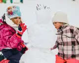 Bambini creano un pupazzo di neve in montagna, un vero natale in montagna con bambini che si divertono nella neve.