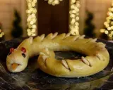 Dolci tipici Perugia: un serpente di pasta frolla dorata, con occhi rossi e lingua arancione, adagiato su un piatto scuro.