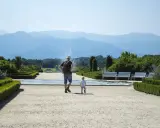 Un uomo e un bambino passeggiano in un giardino curato, con fontane e montagne sullo sfondo. Una giornata perfetta in Piemonte con bambini.