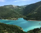 Un lago turchese incastonato tra colline verdi, ideale per il trekking nelle Marche.