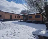 Agriturismo Acqua Bianca imbiancato dalla neve. Un paesaggio invernale incantevole con edifici color pesca e un cielo azzurro con nuvole bianche.