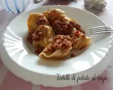 Tortelli di patate al ragù, un piatto gustoso e confortante, servito su un piatto bianco con una forchetta.