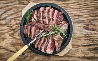 Una succulenta bistecca fiorentina affettata, guarnita con rosmarino, pronta per essere gustata.