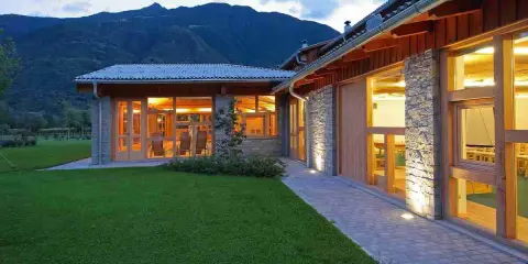 Agriturismi con fattoria immersi nel verde, con architettura in pietra e legno, illuminati al tramonto.