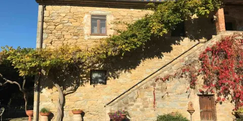 Agriturismi pet friendly in Umbria: casa in pietra con scala esterna e rampicanti colorati, ideale per vacanze con animali.