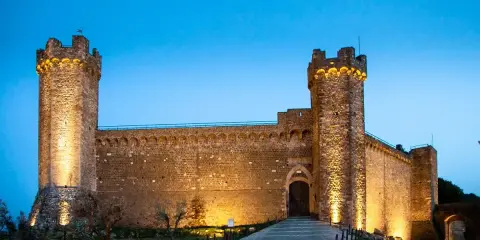 Fortezza illuminata al crepuscolo, simbolo del centro storico di Montalcino. Un'antica roccaforte che domina il paesaggio toscano.