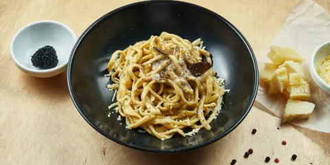 Un piatto di pasta al tartufo, un sapore autentico del cibo perugino, con scaglie di parmigiano e pepe nero.