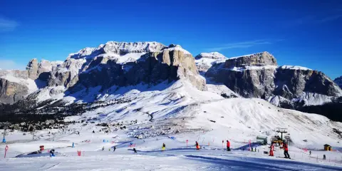 Piste innevate e maestose vette per decidere dove andare a sciare in Trentino. Sciatori e impianti di risalita animano il paesaggio.
