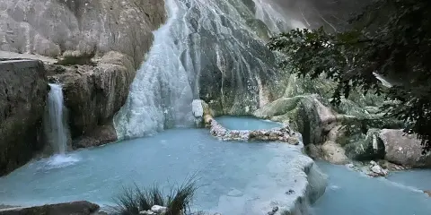 Cascate termali naturali a San Filippo, Toscana, con acque azzurre che scorrono su rocce calcaree.