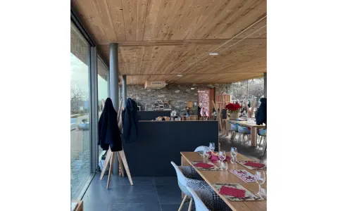 Interno di un agriturismo con tavoli apparecchiati, bancone in pietra e legno. L'agriturismo acqua terra sole offre un'atmosfera accogliente.