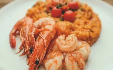 Risotto rosso con gamberi, un piatto tipico di Pavia, guarnito con pomodorini freschi.
