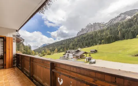 Vista da un balcone su una casa di montagna con prati verdi e boschi. Perfetta per una vacanza in montagna estate.