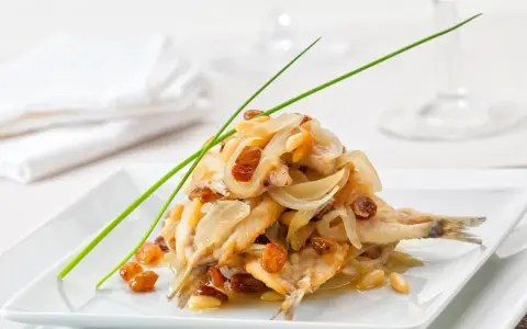 Sardine in saor, un classico dei piatti tipici veneti, con cipolle caramellate, uvetta e pinoli.