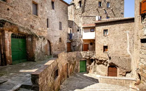 Un vicolo stretto con scale di pietra e case antiche in tufo, un'atmosfera da piccola Gerusalemme.