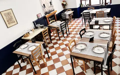 Tavoli apparecchiati in un ristorante, pronti per un'esperienza di **mangiare in Umbria**. Pavimento a scacchi, sedie in legno e dettagli eleganti.