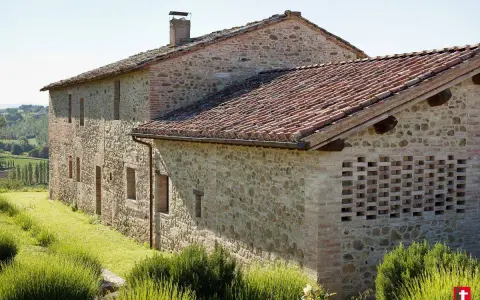 Un casale in pietra e mattoni, ideale per vacanze in Umbria montagna, immerso nel verde con tetto in coppi e un muro traforato.