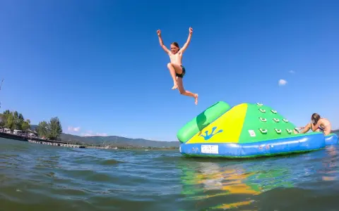 Bambini si divertono sul lago Trasimeno, uno salta da un gonfiabile mentre un altro si riposa.