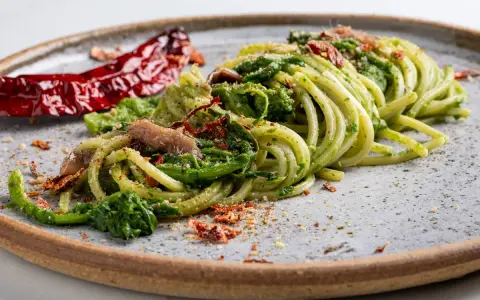 Spaghetti verdi con verdure, acciughe e peperoncino secco, un piatto tipico Basilicata che evoca sapori autentici.