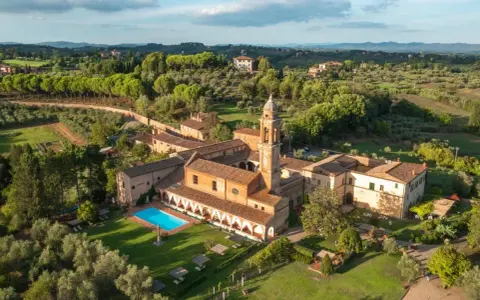 Un'antica dimora con campanile e una splendida piscina toscana, immersa nel verde delle colline.