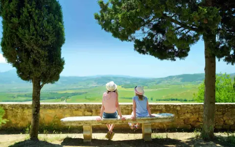 Due bambine con cappello ammirano il panorama collinare toscano, un perfetto weekend con bambini in Toscana.