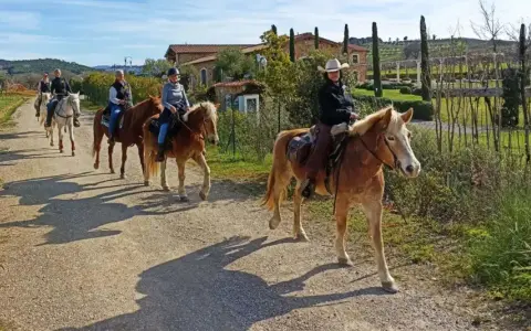 Cavalcata in un maneggio toscana, tra colline verdi e casali antichi.