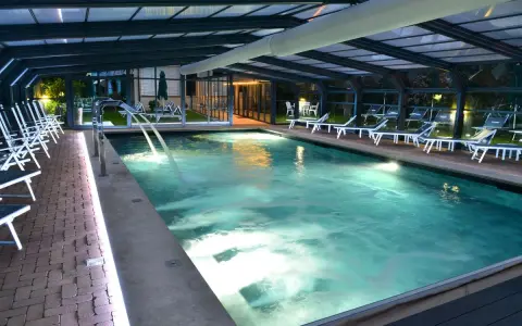 Piscina coperta con lettini e cascate d'acqua, un'oasi di relax tra le migliori spa in Umbria.