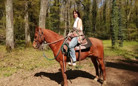 Donna a cavallo in un bosco del Lazio, godendosi una tranquilla passeggiata a cavallo.