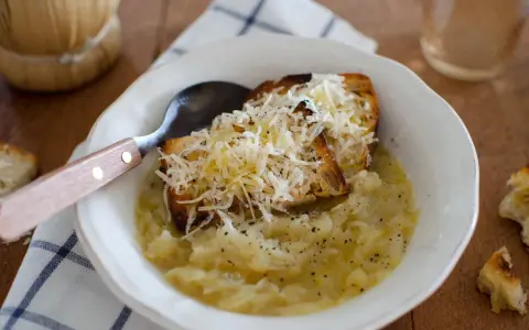 Zuppa di cipolle fumante con crostini gratinati al formaggio, un comfort food che ricorda la carabaccia.