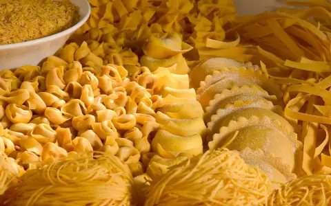 Varietà di pasta fresca, tra cui tortellini, ravioli e tagliatelle, che rappresentano i piatti tipici dell'Emilia Romagna.