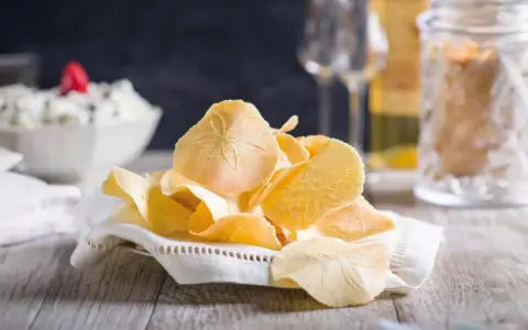 Delicati cialde, un dolce tipico toscano, su un tovagliolo ricamato. Sullo sfondo, una ciotola con crema e bicchieri.