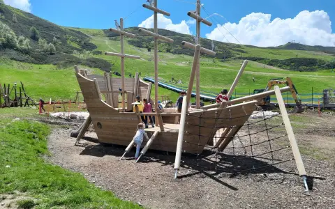 Un grande galeone di legno su un prato verde, perfetto per agriturismi per bambini in Piemonte. Bambini giocano a bordo.