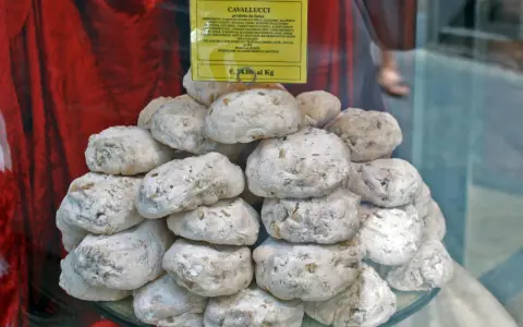 Dolce senese: cavallucci, biscotti rustici con noci e agrumi, impilati su un piatto di vetro.