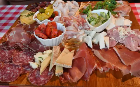 Tagliere ricco con salumi, formaggi, pomodori e sottaceti, un assaggio dei piatti tipici del Friuli Venezia Giulia.