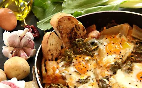 Uova cotte in padella con verdure, patate, aglio, peperoncino e pane tostato. Un piatto rustico e saporito, perfetto per una colazione o un pasto veloce.