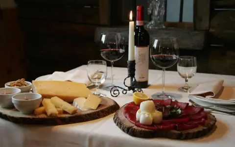 Tagliere con formaggi e bresaola, accompagnati da vino rosso e candela. Un assaggio dei piatti tipici Valtellina.
