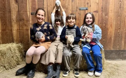 Bambini felici durante un'attività fattoria, tengono in braccio coniglietti soffici.