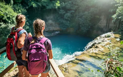 Due ragazze con zaini ammirano una cascata durante un trekking in Toscana montagna.