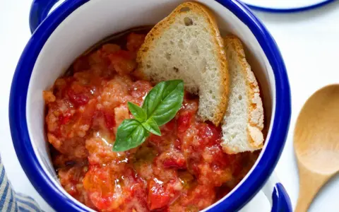Pappa al pomodoro, un piatto che racconta la sua origine toscana. Servita in ciotola con pane raffermo, pomodoro e basilico fresco.