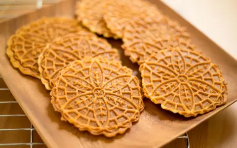Pizzelle, dolci tradizionali abruzzesi, su un piatto di legno.