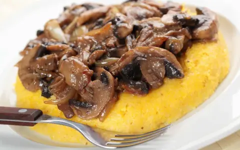 Polenta con funghi trifolati, un classico tra i cibi tipici del Trentino Alto Adige, pronta per essere gustata.