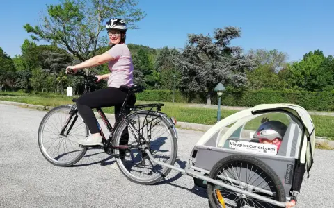 Donna in bici con rimorchio per bambini, pronta per le vacanze in bici con bambini.
