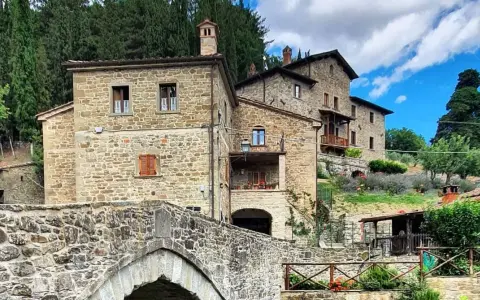 Antico ponte in pietra e case in pietra, tipici dei borghi vicino Arezzo, immersi nel verde della campagna toscana.